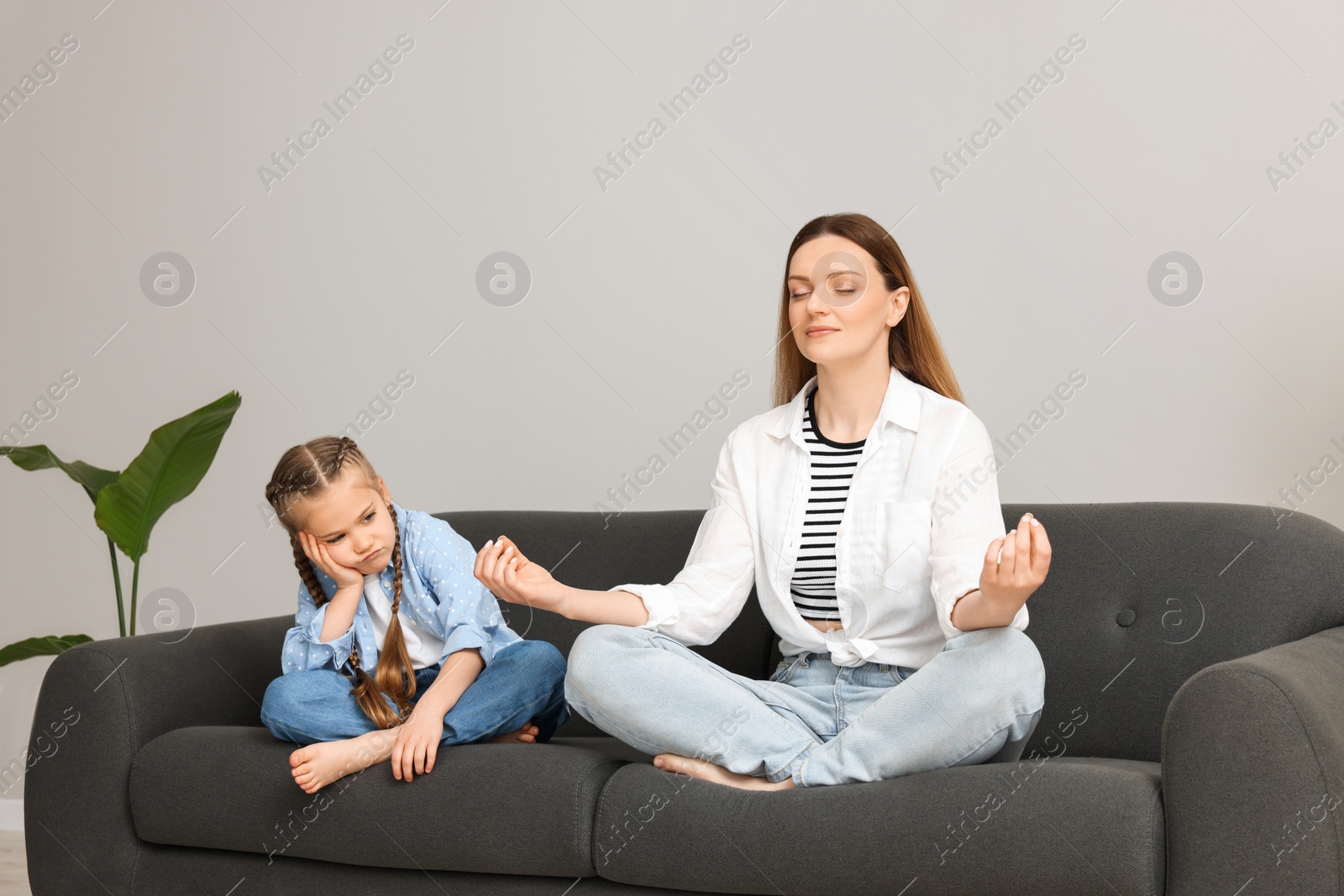 Photo of Mother meditating while her daughter getting bored at home