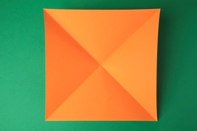 Photo of Origami art. Sheet of paper on green background, top view