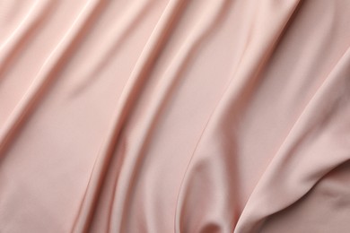 Crumpled pink silk fabric as background, top view