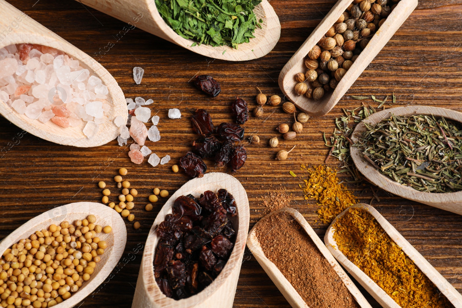 Photo of Scoops with different spices on wooden table, flat lay