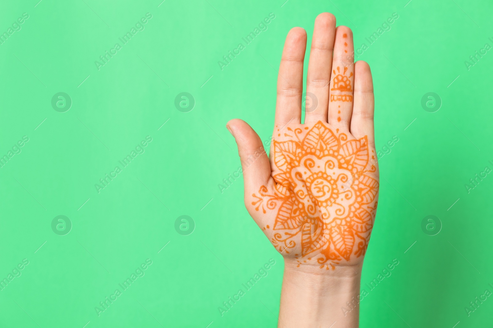 Photo of Woman with henna tattoo on palm against green background, closeup and space for text. Traditional mehndi ornament