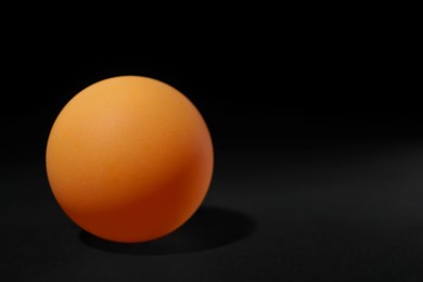 Photo of One ping pong ball on black background, space for text