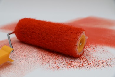 Photo of Roller brush and strokes of orange paint on white background, closeup