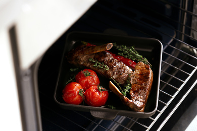 Photo of Delicious roasted ribs with tomatoes in oven