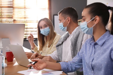 Photo of Coworkers with masks in office. Protective measure during COVID-19 pandemic