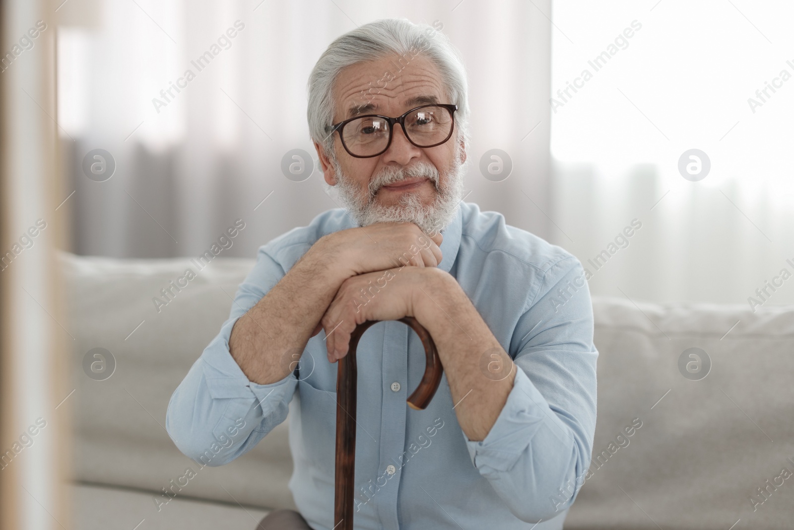 Photo of Portrait of grandpa with glasses and walking cane on sofa indoors