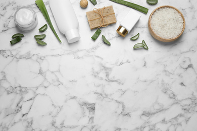 Flat lay composition with aloe vera and cosmetic products on white marble background. Space for text