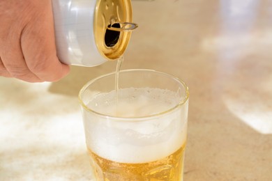 Photo of Man pouring beer from can into glass at table, closeup. Space for text