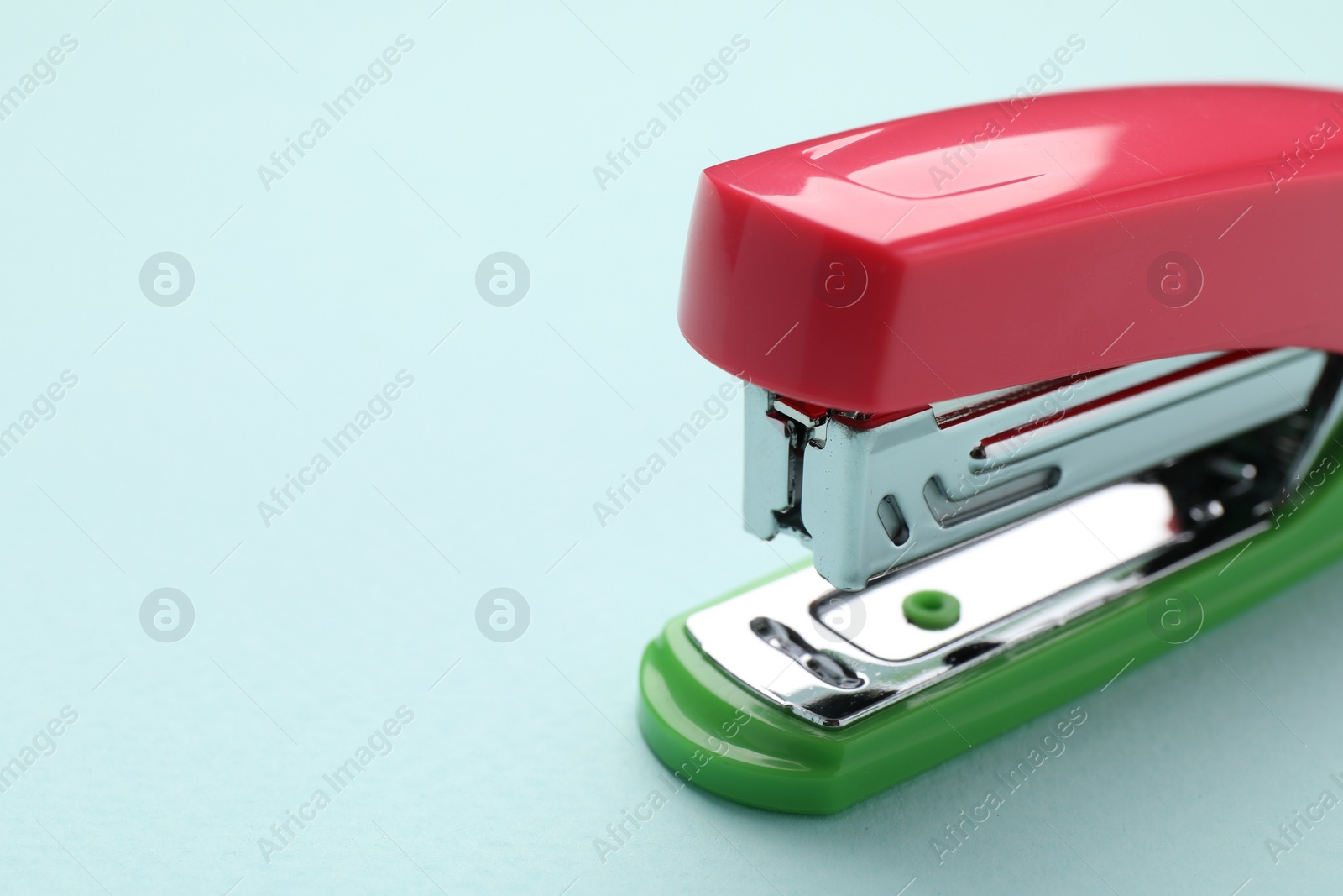 Photo of One bright stapler on light blue background, closeup. Space for text