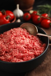 Photo of Fresh minced meat and spoon in bowl on table, closeup