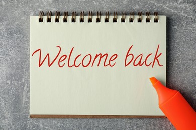 Image of Notebook with phrase Welcome Back and highlighter on grey table, top view