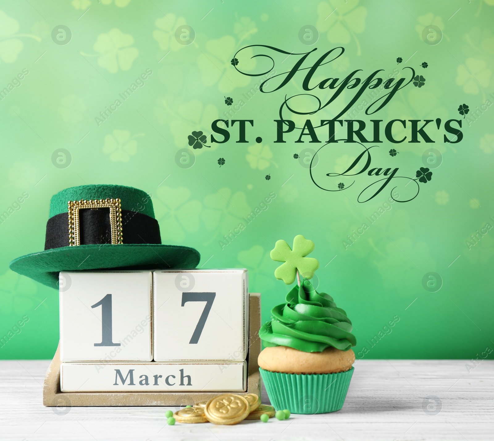 Image of Decorated cupcake, wooden block calendar, hat and coins on white table. St. Patrick's Day celebration