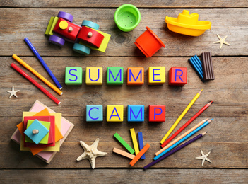 Flat lay composition with phrase SUMMER CAMP made of colorful cubes on wooden background