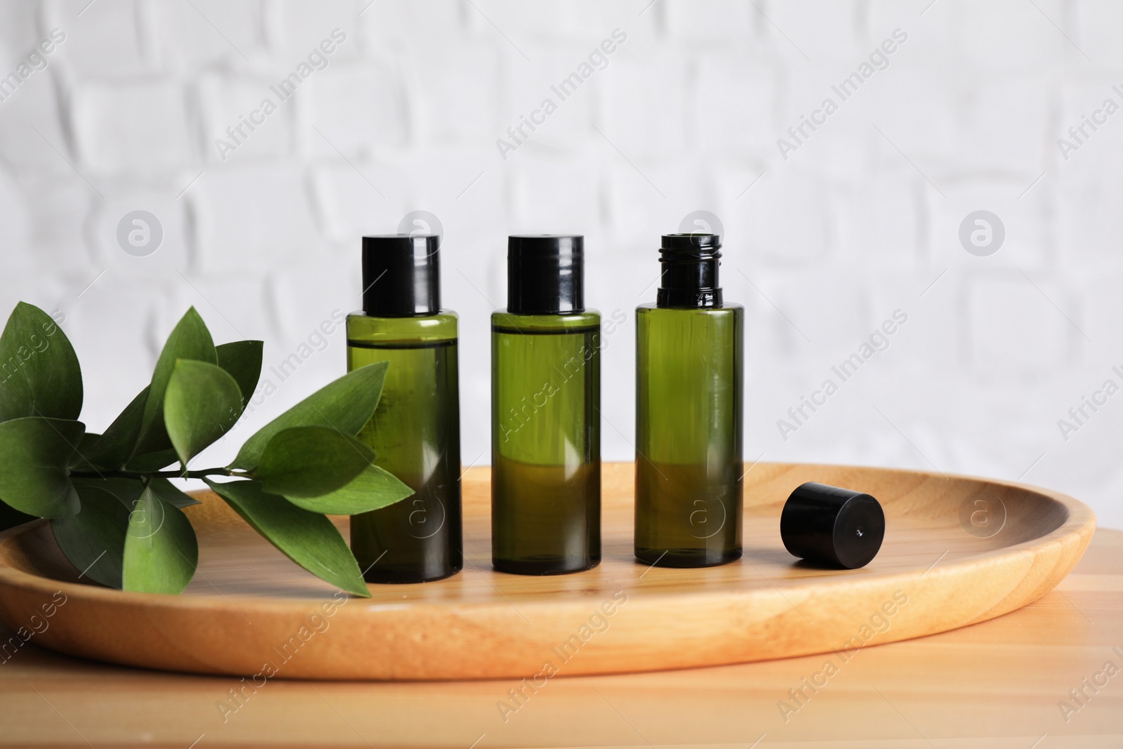 Photo of Mini bottles with cosmetic products on wooden table against white background