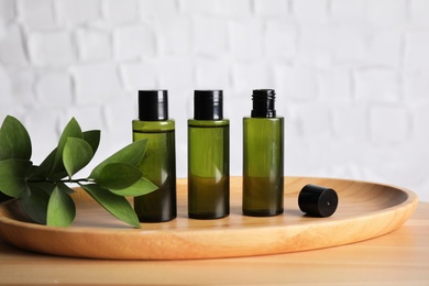 Mini bottles with cosmetic products on wooden table against white background