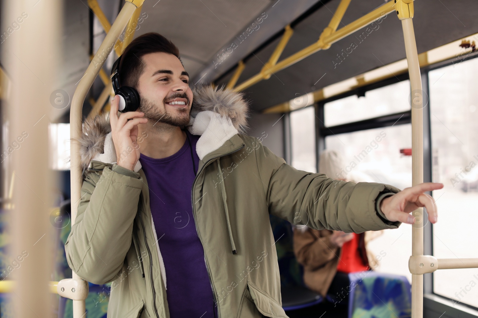 Photo of Young man listening to music with headphones in public transport