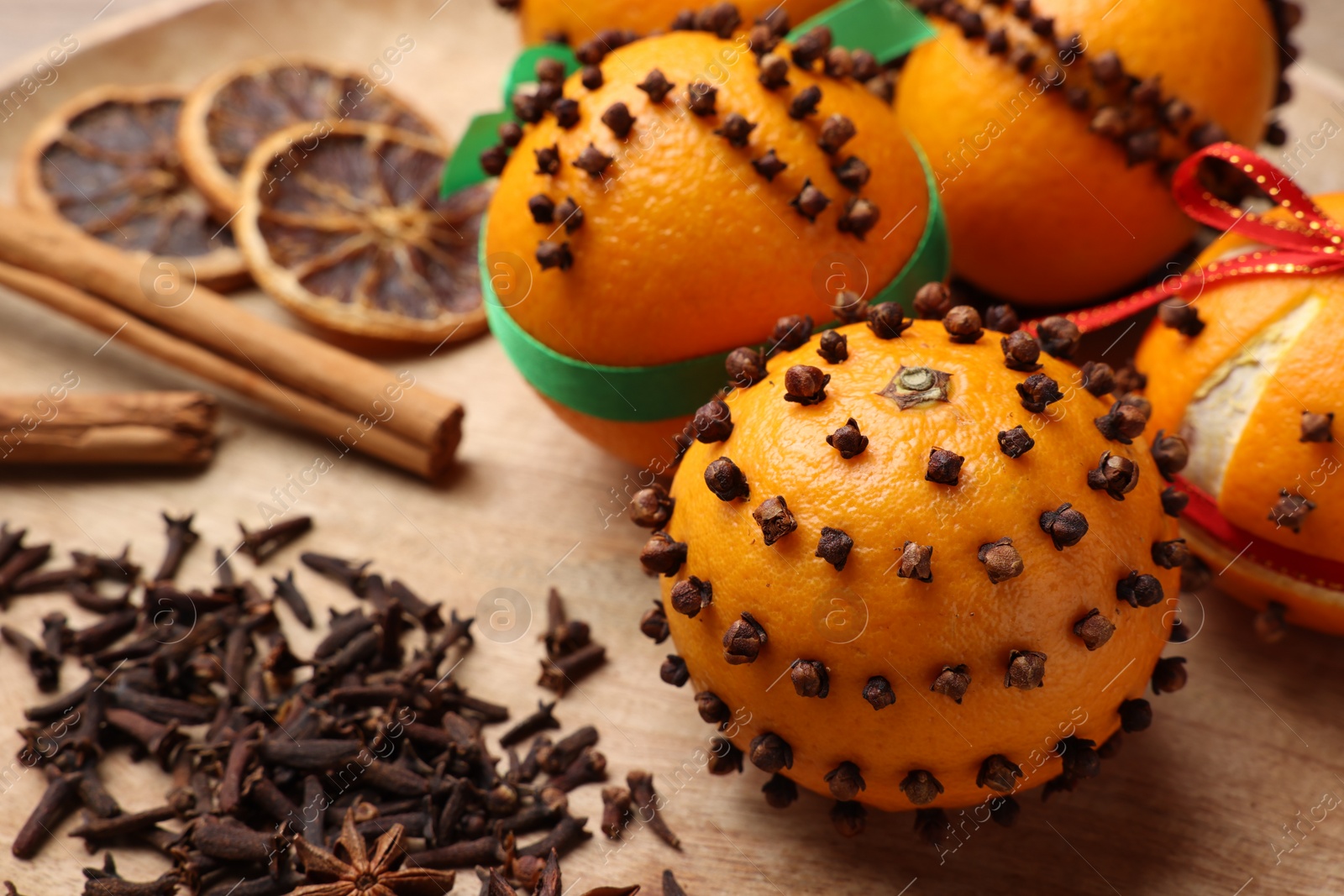 Photo of Pomander balls made of tangerines with cloves on wooden table, closeup