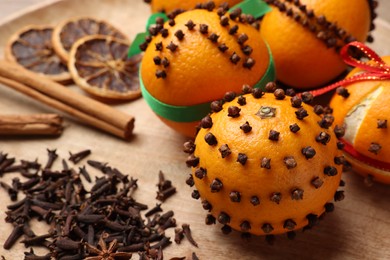 Pomander balls made of tangerines with cloves on wooden table, closeup