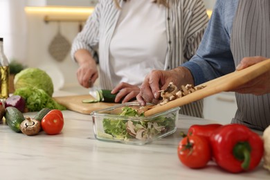 Photo of Senior couple cooking together in kitchen, closeup