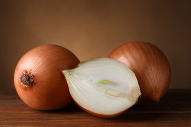 Photo of Whole and cut onions on wooden table, closeup