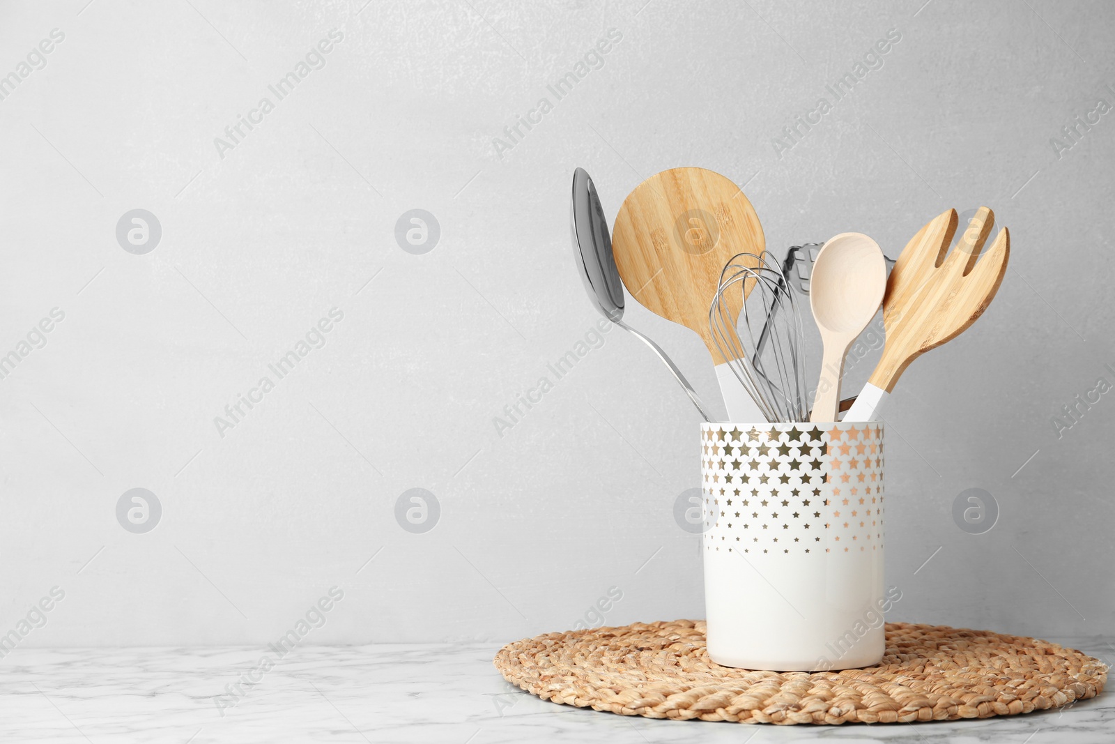 Photo of Different kitchen utensils on table against light background. Space for text