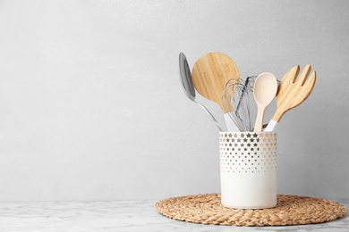 Photo of Different kitchen utensils on table against light background. Space for text