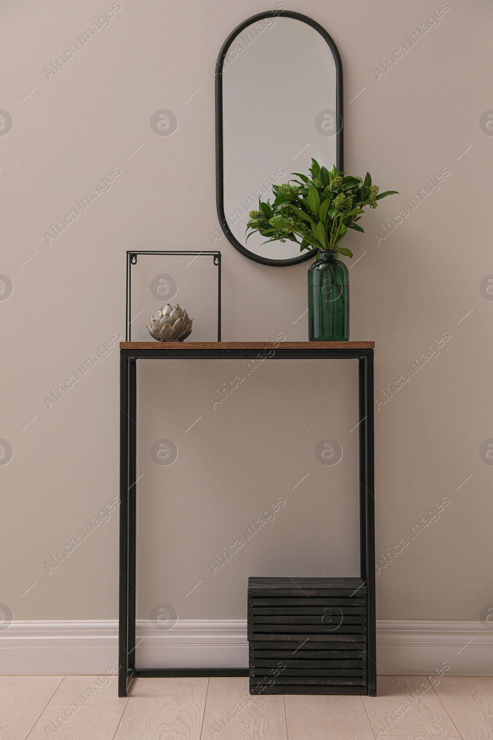 Photo of Console table with decor and mirror on light wall in hallway. Interior design