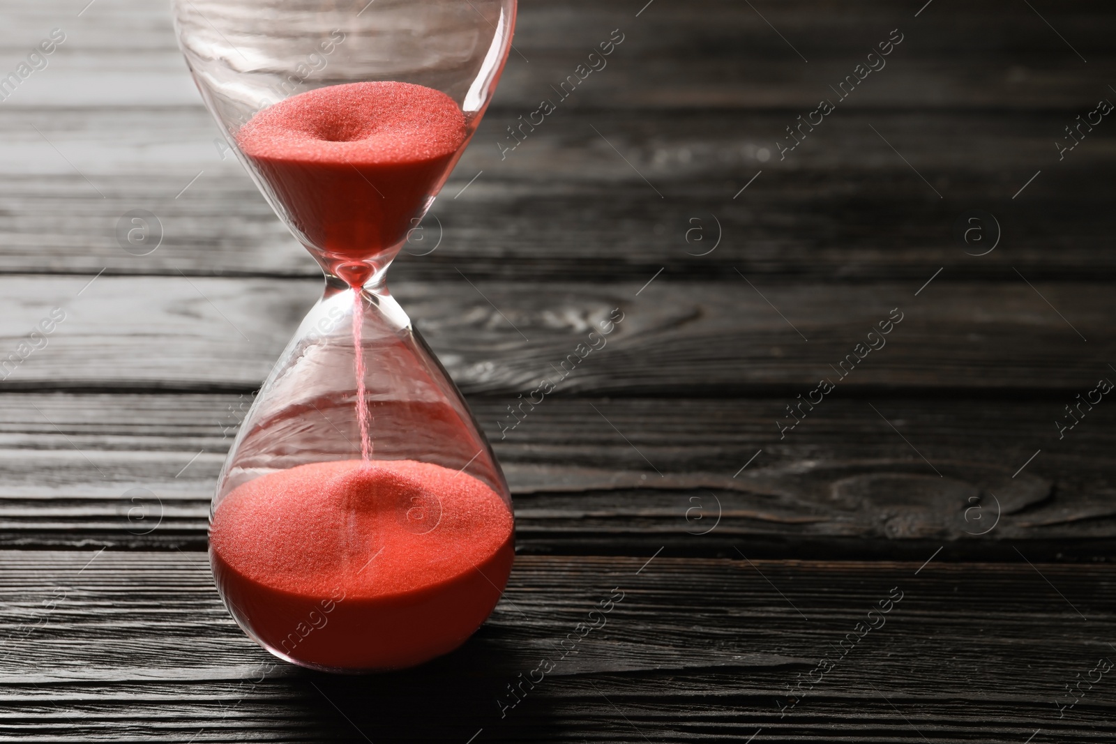 Photo of Hourglass with flowing sand on table. Time management