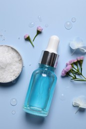 Bottle of cosmetic serum, beautiful flowers and sea salt on light blue background, flat lay