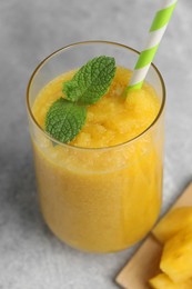 Glass of tasty pineapple smoothie with mint on light gray table, closeup