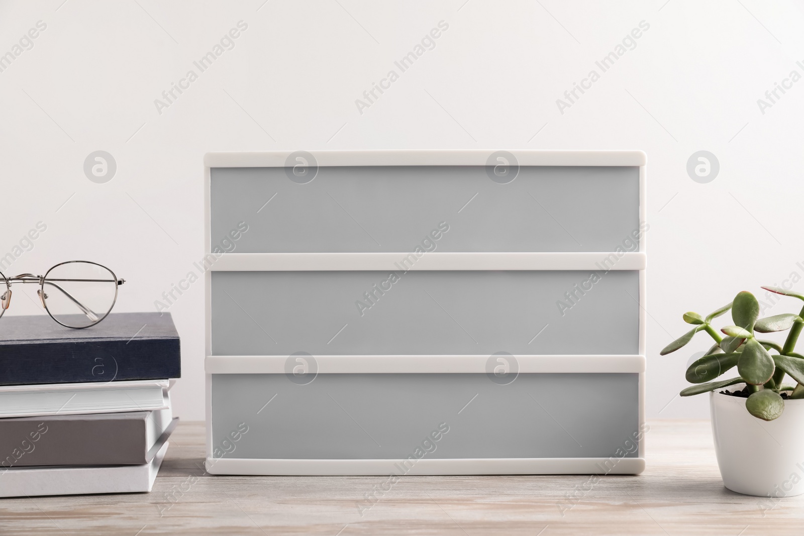 Photo of Blank letter board, books, glasses and beautiful houseplant on wooden table. Mockup for design