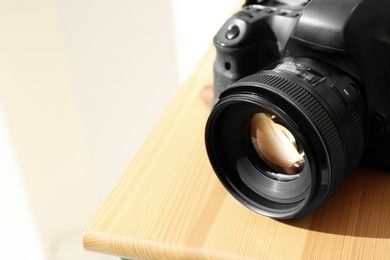 Professional camera on wooden table, space for text. Photographer's equipment