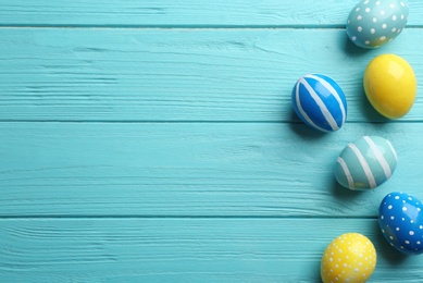 Photo of Flat lay composition of painted Easter eggs on wooden table, space for text