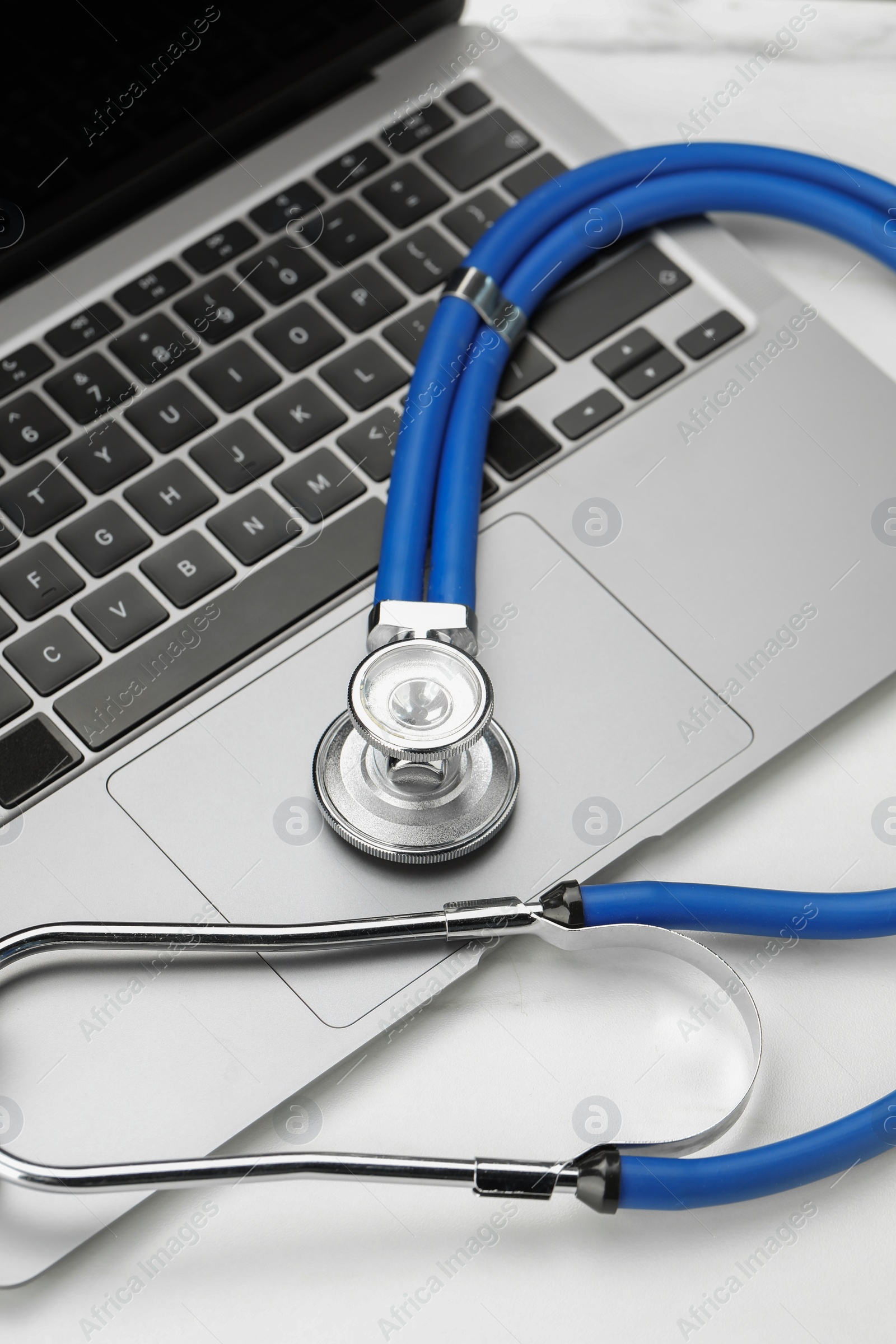 Photo of Stethoscope and modern laptop on white table