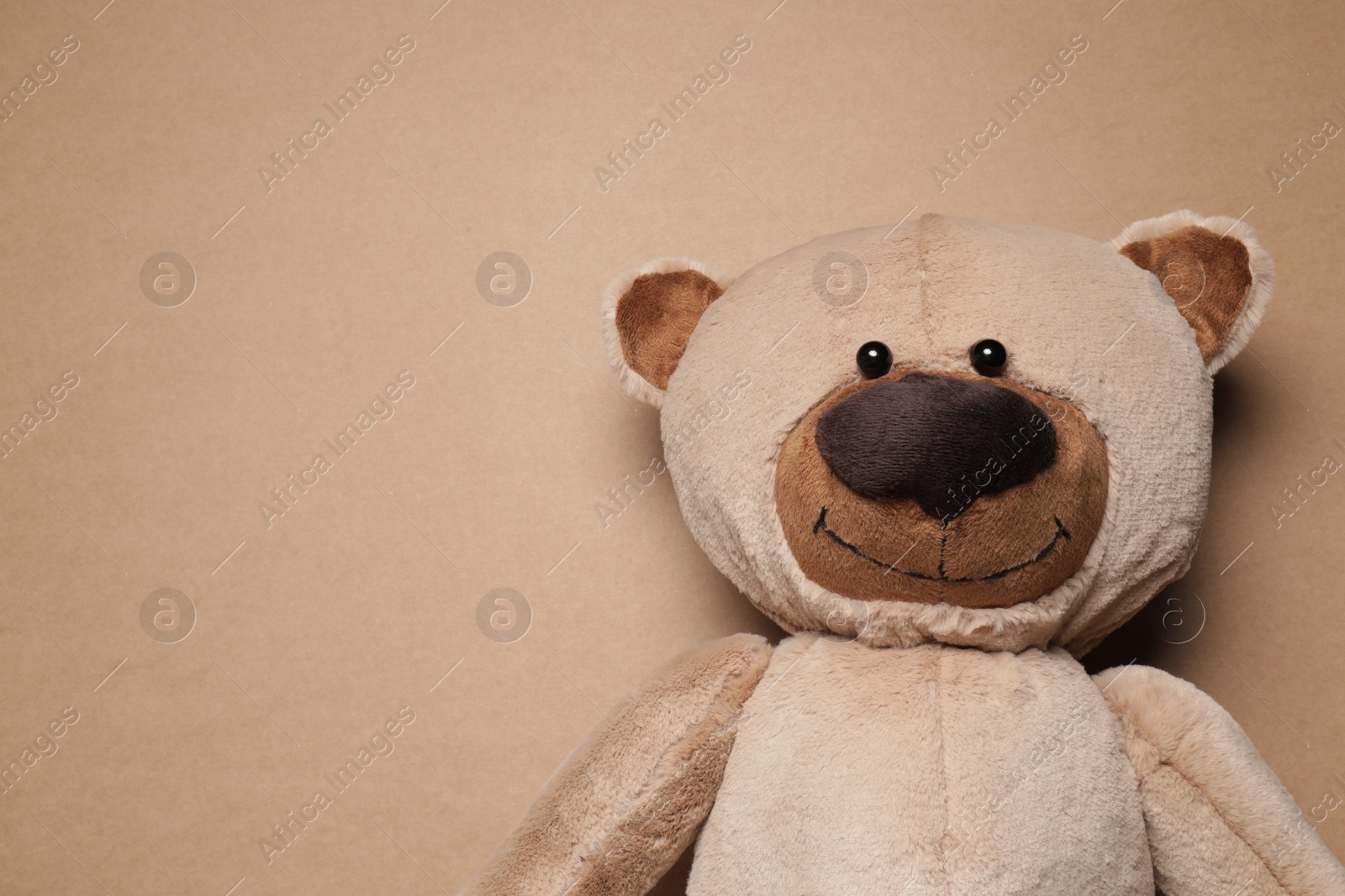 Photo of Cute teddy bear on brown background, top view. Space for text