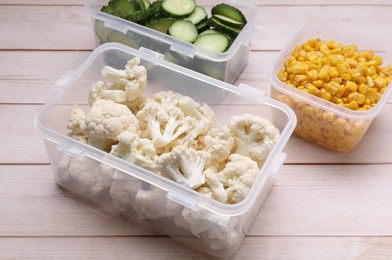 Plastic containers with different fresh products on white wooden table