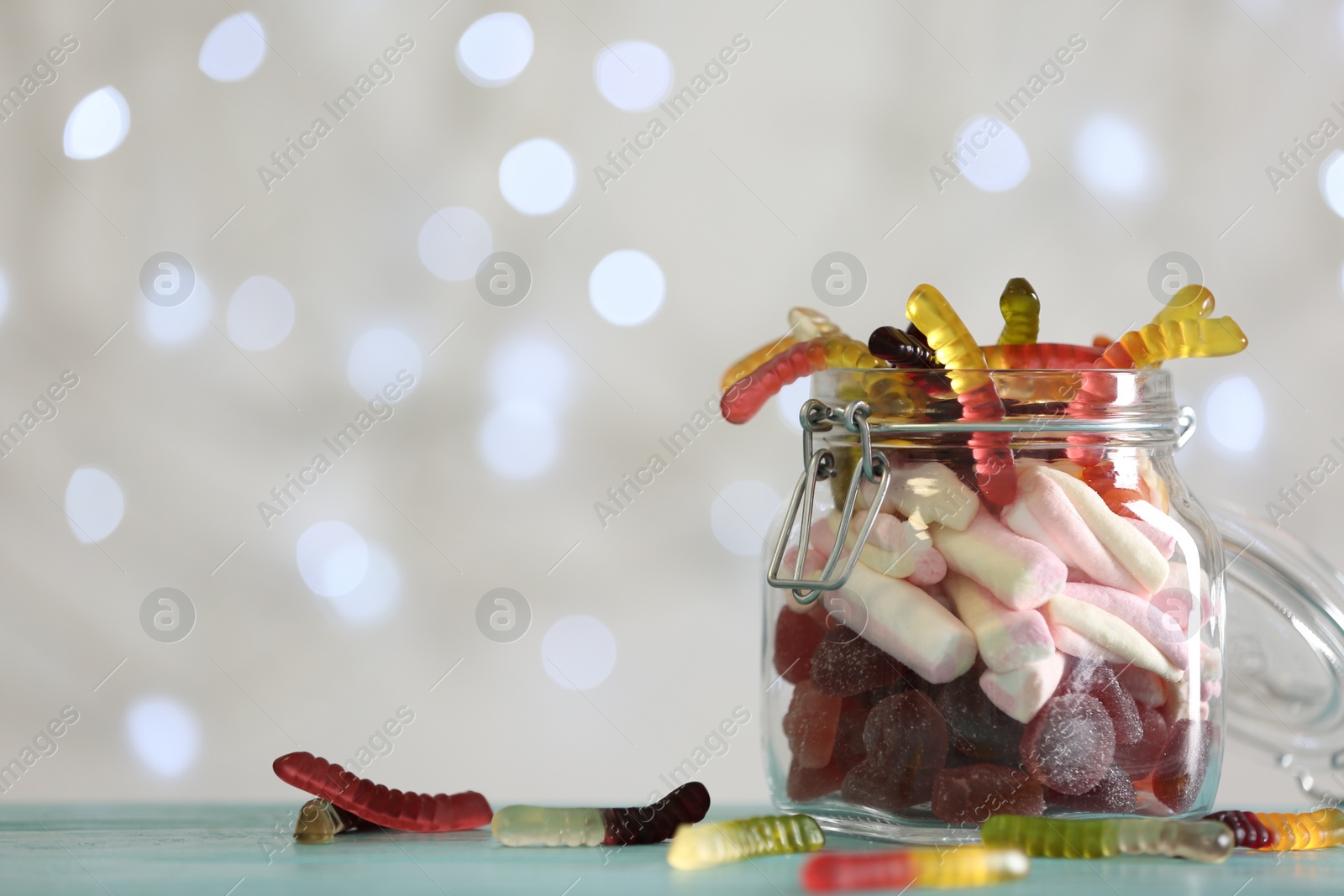 Photo of Delicious candies in jar on table against blurred background, closeup. Space for text