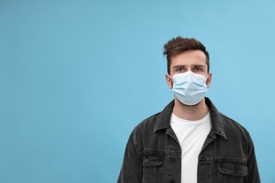 Photo of Portrait of man with medical mask on light blue background, space for text