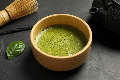 Photo of Cup of fresh matcha tea on black table, closeup