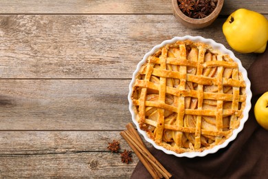 Photo of Tasty homemade quince pie with fresh fruits and spices on wooden table, flat lay. Space for text