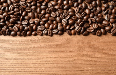 Photo of Roasted coffee beans on wooden background with space for text, top view