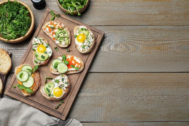 Different delicious sandwiches with microgreens on wooden table, flat lay. Space for text