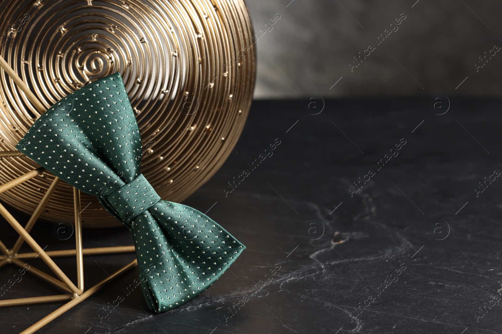 Photo of Stylish presentation of green bow tie on black table, space for text