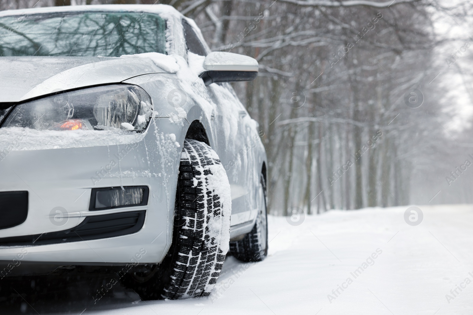 Photo of Car with winter tires on snowy road in forest, space for text