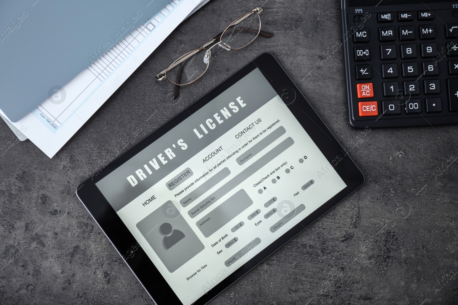 Photo of Tablet with driver's license application form, glasses and calculator on grey table, flat lay