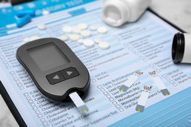 Photo of Digital glucometer and medicine on form for laboratory test. Diabetes concept