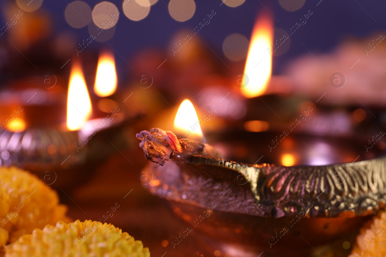 Photo of Diwali celebration. Diya lamps on table against blurred lights, closeup