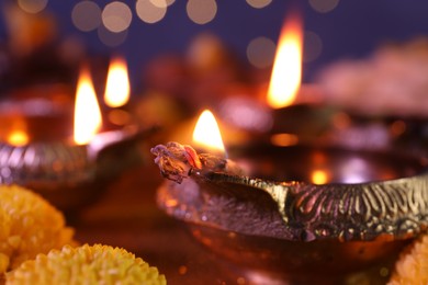 Photo of Diwali celebration. Diya lamps on table against blurred lights, closeup