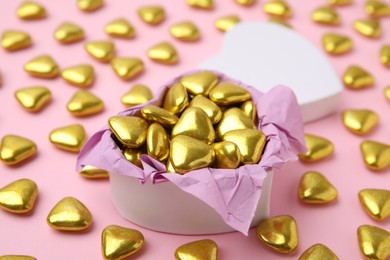 Box and delicious heart shaped candies on pink background