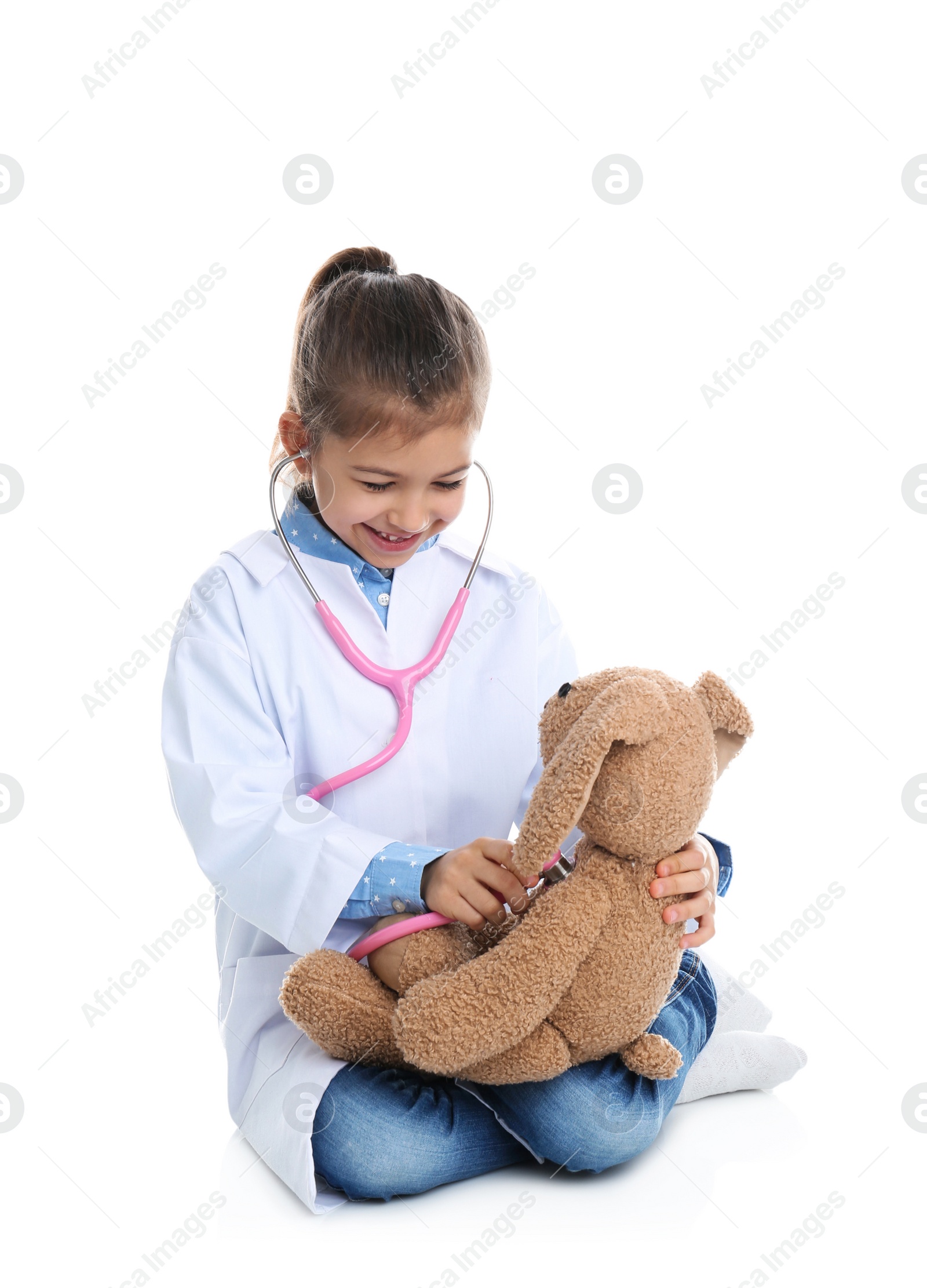 Photo of Cute child playing doctor with stuffed toy on white background